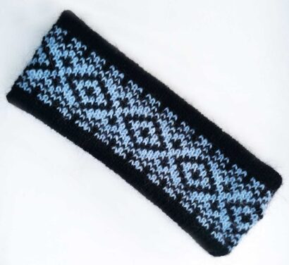 Dieses Foto zeigt ein selbst gestricktes Stirnband aus Wolle. Das Stirnabnd hat zwei Farben: Schwarz und Hellblau. Das Stirnband ist im sogenannten Fair-Isle-Strickmuster gestrickt. Das Foto dient zur Visualisierung der kostenlosen Strickanleitung für ein Stirnband im Fair-Isle-Muster.