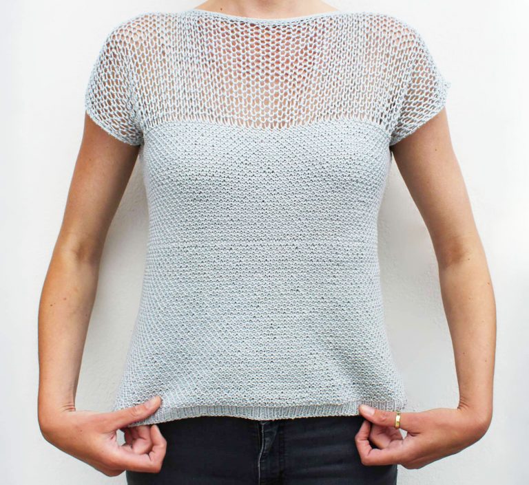 Nahaufnahme einer Frau, die ein pastellfarbenes, selbst gestricktes Sommertop mit einem feinen Lochmuster im Bereich der Passe trägt.